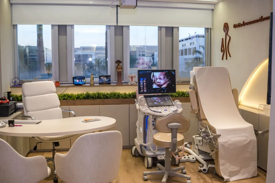 Mesa com poltronas para a família acompanhar o exame, ao lado do aparelho de ultrassom
